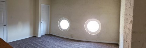 two round windows in a white room with a door